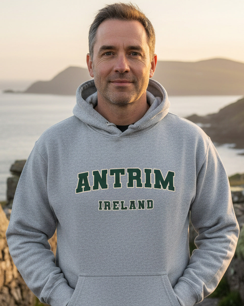 Man in grey Antrim Ireland hoodie outdoors by scenic Irish coastline