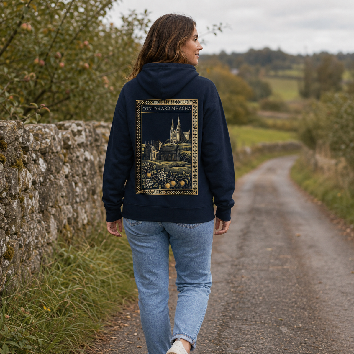 Woman wearing the navy Armagh Heritage Hoodie from the back on a quiet orchard lane
